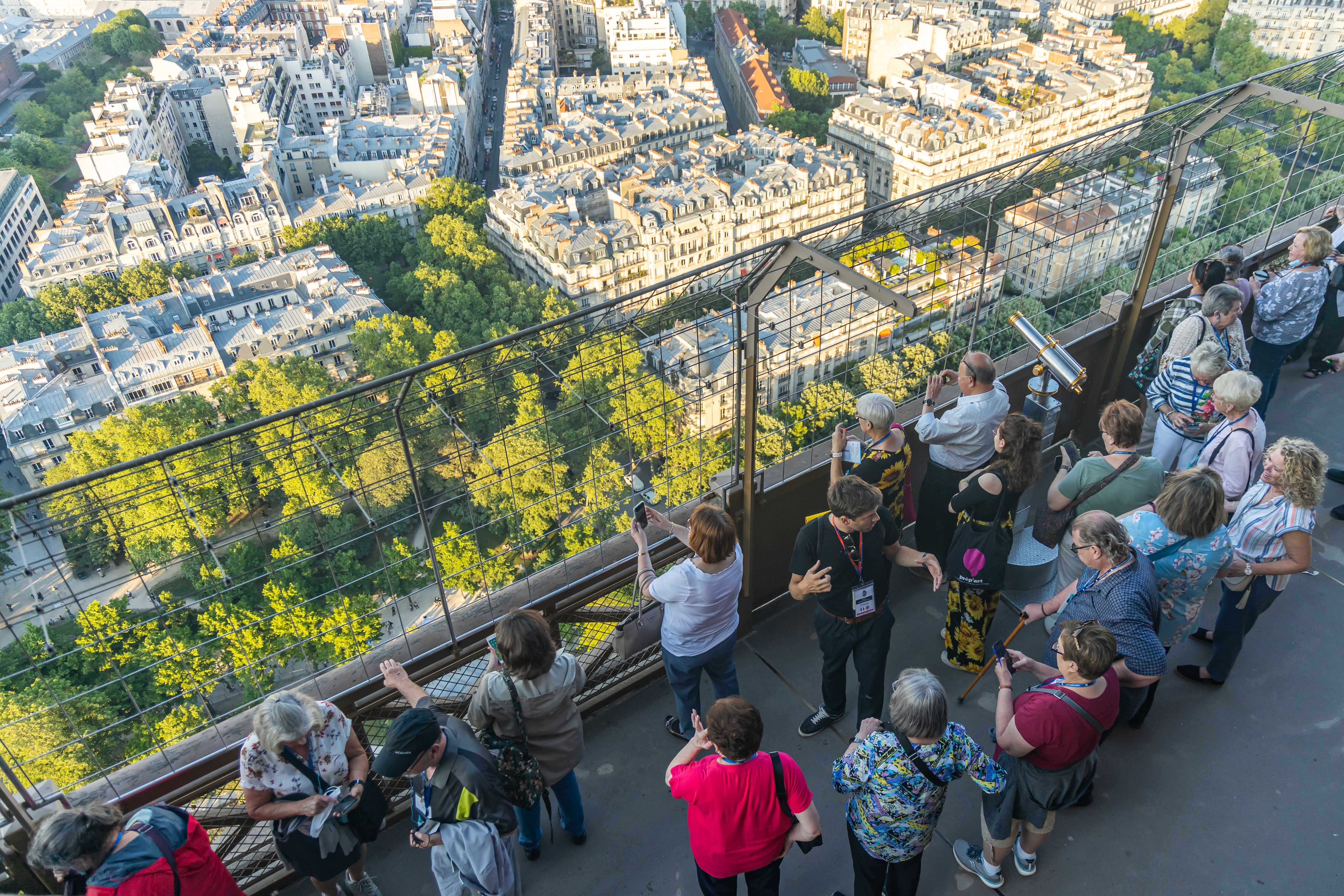 Tourists looking down at Paris while visiting the second floor of the Eiffel Tower